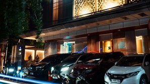 A hotel with a modern facade, a prominent 'QUBE' sign, and several parked cars in front. - Qube Hotel by 98hospitality (Jakarta)