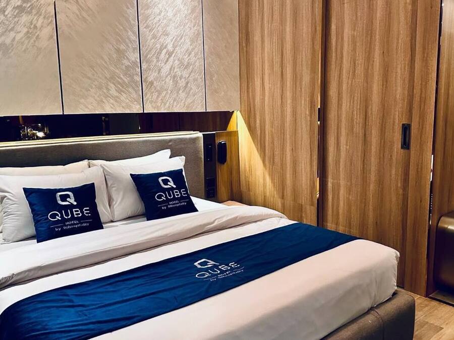 Una habitación de hotel con cama, mesita de noche, armario y lámpara.