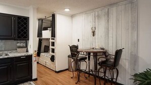 A compact kitchen with dark cabinets, a marble countertop, and a dining area with a round table and two chairs. - Cozy Condo in Ruidoso ideal for Outdoor Enthusiasts!  (Ruidoso)
