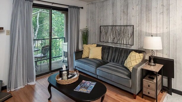 A modern living room with a grey sofa, a black coffee table, and a lamp. - Cozy Condo in Ruidoso ideal for Outdoor Enthusiasts!  (Ruidoso)