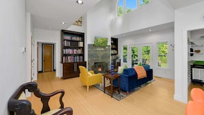 A spacious living room with a fireplace, bookshelves, and a large window. - Sullivan Farm at Helton Creek - Fire Pit - Foosball - Fireplace (Lansing)