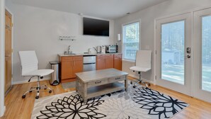 Een moderne keuken met een eettafel, twee stoelen, een televisie en een groot raam.