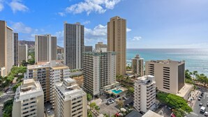 A high-rise hotel with multiple floors, a rooftop pool, and a view of the ocean.