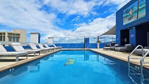 A swimming pool with lounge chairs and a mural on the adjacent wall.