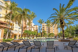 A pool area with lounge chairs, palm trees, and a building with balconies. - Fully Renovated Condo with and Extraordinary view! (Aventura)