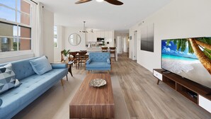Una sala de estar moderna con un sofá azul, una mesa de centro de madera y un televisor sobre un mueble de madera.