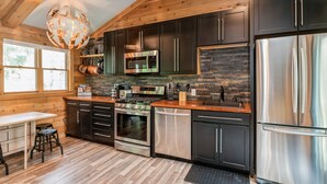 A modern kitchen with dark cabinets, stainless steel appliances, and a wooden ceiling. -  A cozy, modern cottage has all the amenities and privacy a hotel cannot offer. (Lake Geneva)