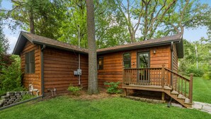 A wooden cabin with a porch and a staircase leading to a deck. -  A cozy, modern cottage has all the amenities and privacy a hotel cannot offer. (Lake Geneva)