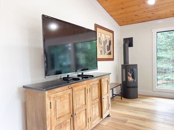 Un salon moderne doté d’un téléviseur à écran plat, d’un meuble en bois et d’un poêle à bois.