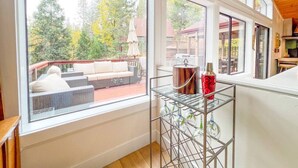 A room with large windows, a metal rack with glassware, and a view of an outdoor deck.