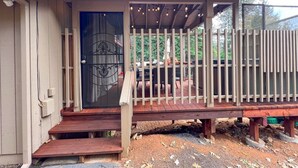 A wooden deck with a railing, a door with a decorative glass panel, and a small porch area.