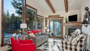 Un salón amplio con ventanas grandes, chimenea y televisor.