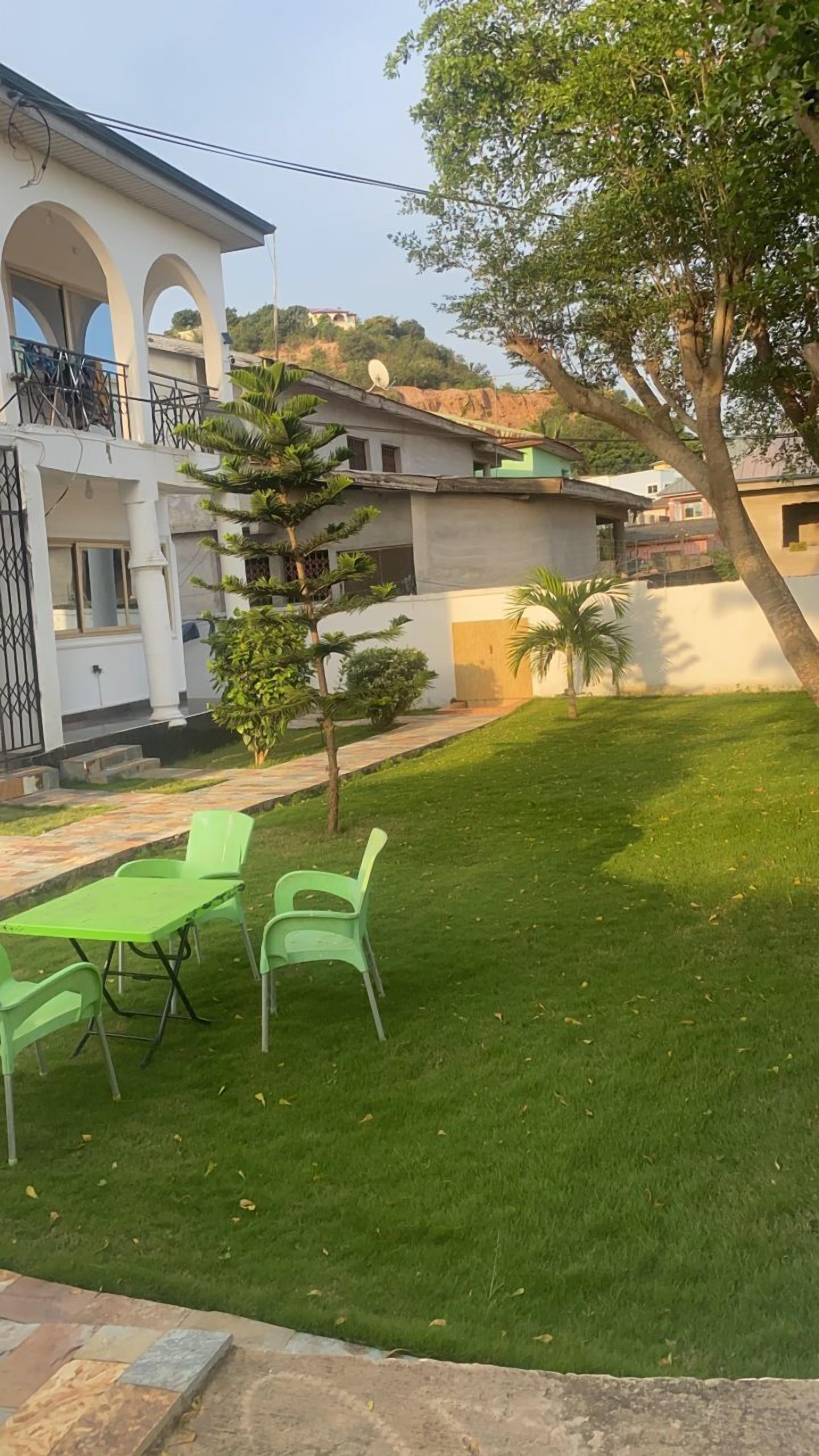 A residential area with a well-maintained lawn, a dining table with chairs, and a satellite dish on a building.