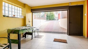 Ein Zimmer mit Bett, kleinem Tisch, Fenster und einer Tür zum Außenbereich.