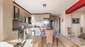 Eine moderne Küche mit Essbereich, ausgestattet mit hellem Holzkorpus, Edelstahlgeräten und einer zentralen Kochinsel.