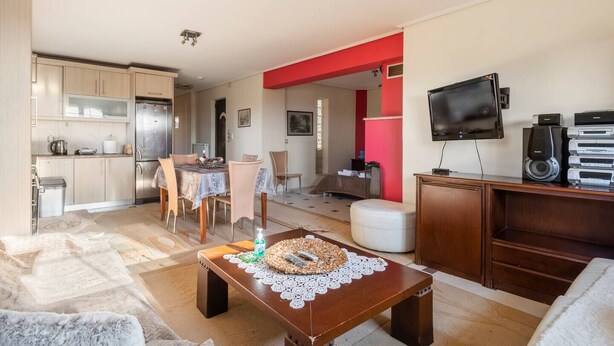Eine moderne Wohnung mit Küche, Essbereich und Wohnzimmer. Sie verfügt über einen Flachbildfernseher, eine Kaffeemaschine und einen Esstisch mit Stühlen.