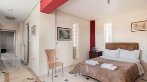 Ein Hotelzimmer mit Bett, Stuhl, Nachttisch und Fenster.
