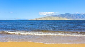A beach with clear blue water, sandy shore, and distant mountains. - Comfort of home, ground floor with in unit laundry (Kihei)