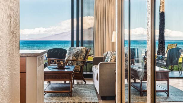 A room with a view of the ocean, featuring a sofa, chairs, and a dining table. - Direct oceanfront views, remodeled condo (Lahaina)
