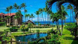 A resort with a pool, palm trees, and a view of the ocean. - Direct oceanfront views, remodeled condo (Lahaina)