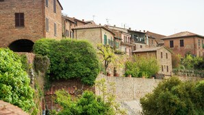 A historic stone building with a brick facade, arched entrance, and surrounding greenery.