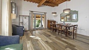 A dining area with a wooden table and chairs, a sofa, and a ceiling with exposed beams.