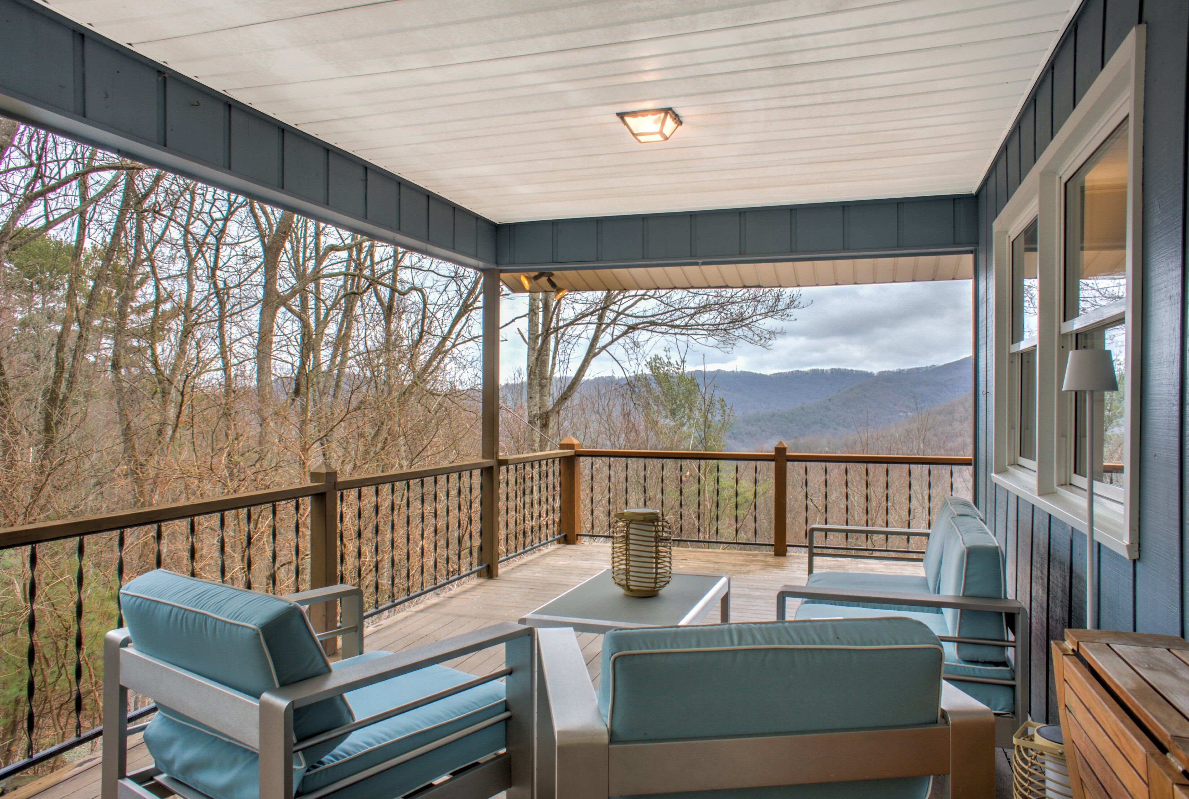A covered outdoor seating area with a view of trees and mountains.