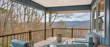 Un espace extérieur abrité, aménagé pour s’asseoir, avec vue sur les arbres et les montagnes.