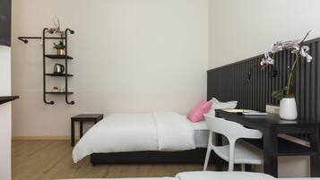 A modern bedroom with a bed, a desk, a chair, a shelf with plants, and a wall-mounted shelf.