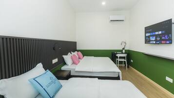 Una habitación de hotel con dos camas, un televisor montado en la pared, una mesita y una silla.