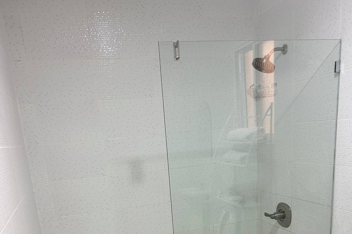 Eine Duschkabine mit Handbrause und am Wand montiertem Wasserhahn.