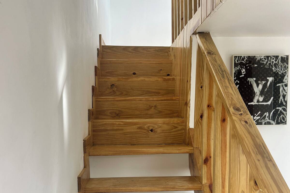 Eine Holztreppe mit Handlauf, weißen Wänden und einem gerahmten Bild an der Wand.