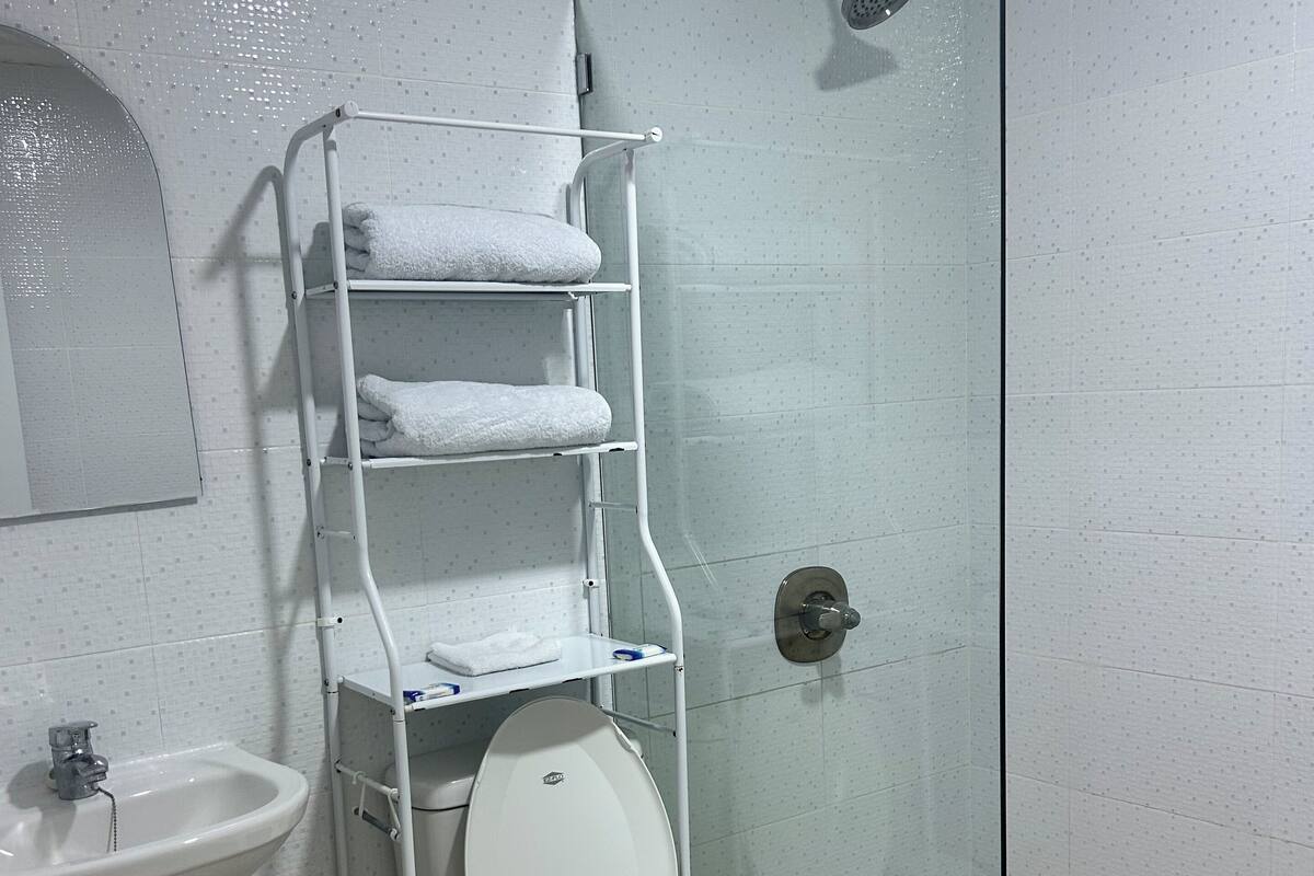 Ein Badezimmer mit Duschkabine, Toilette, Waschbecken und Handtuchhalter.