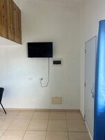 Habitación con una televisión de pantalla plana montada en la pared, un termostato y una puerta con manija.