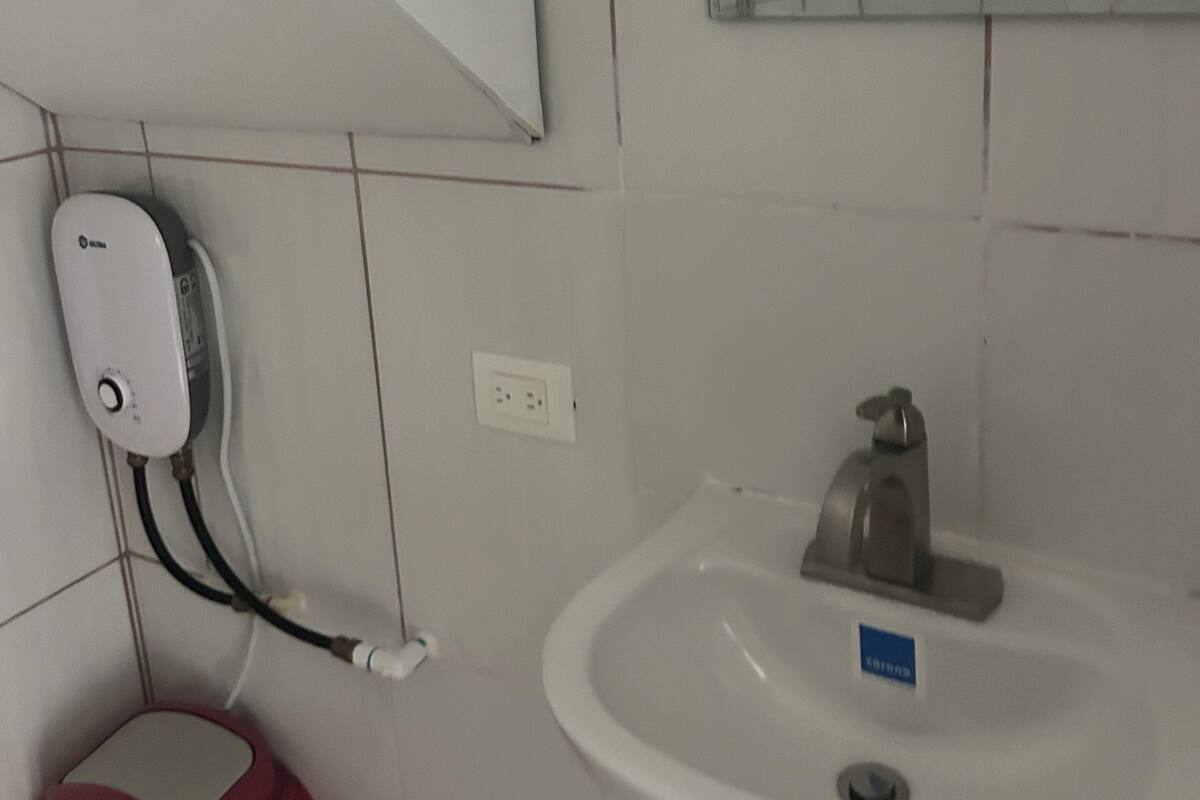 Ein Badezimmer mit einem weißen Waschbecken, einem Spiegel und einer roten Tasche auf dem Boden.