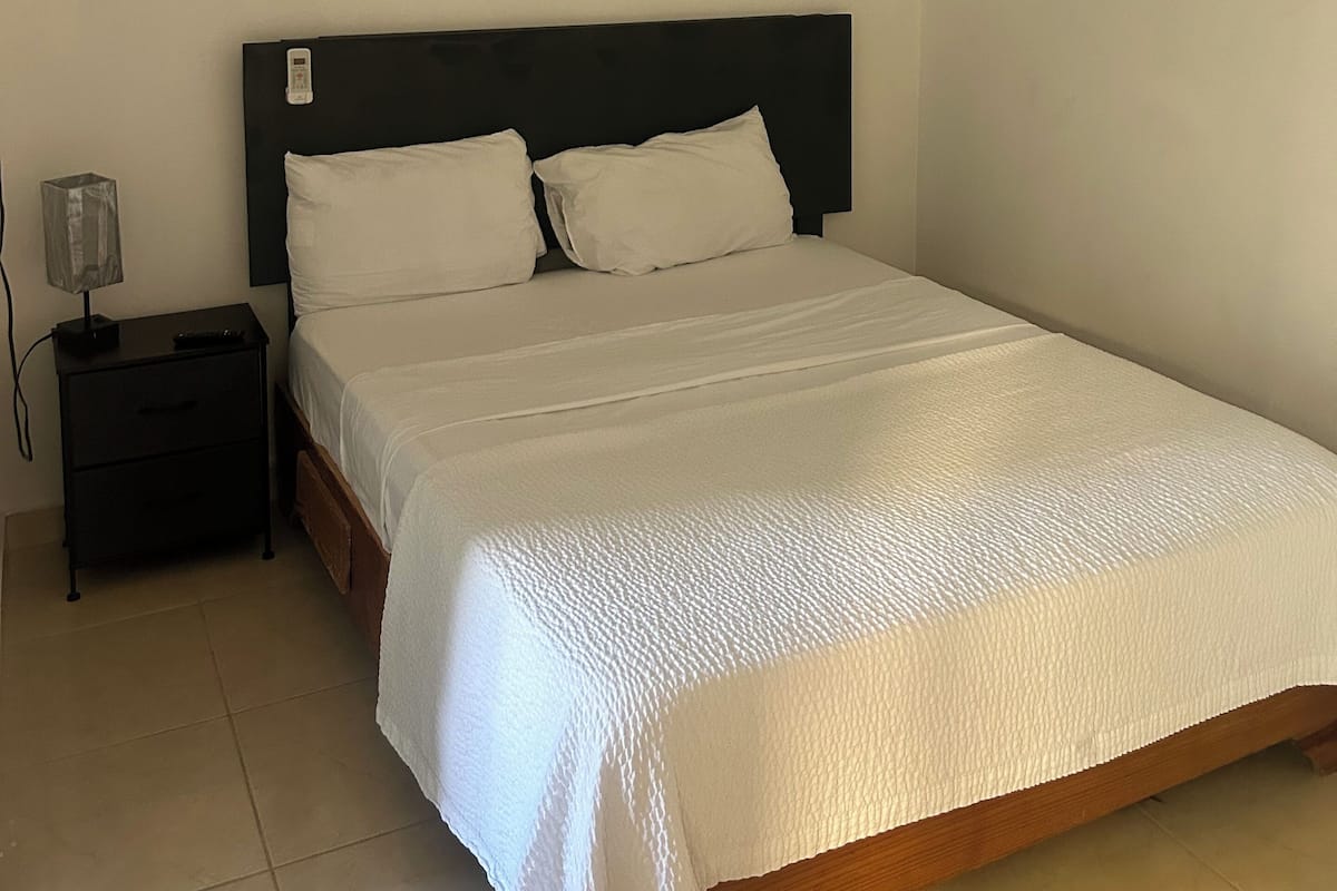 Ein Schlafzimmer mit Bett, Nachttisch, Lampe und Deckenleuchte.