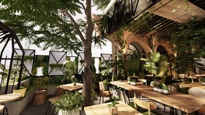An outdoor café with wooden tables and chairs, surrounded by lush greenery and plants. - Posto Dormire Benhil (Jakarta)