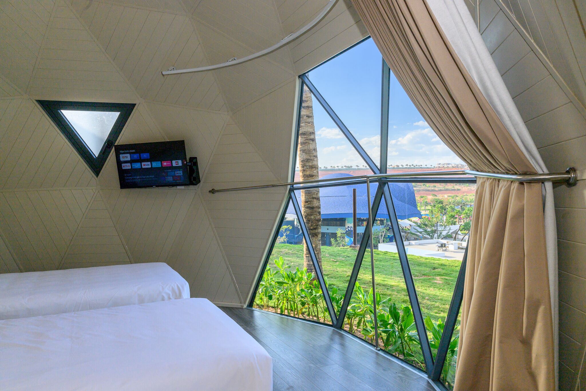 A room with a large window, a bed, and a mounted TV.
