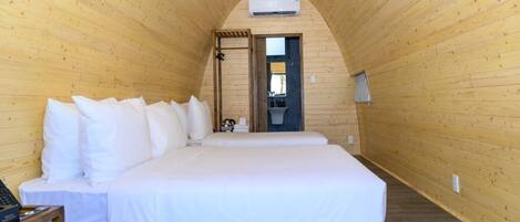 A wooden room with a bed, a small table, and a door leading to a bathroom.