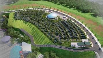 An aerial view of a landscaped property with a central circular area, surrounded by a curved road and a row of trees.