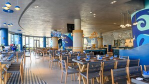 Un restaurante moderno con techos altos, decoración azul y blanca, y una variedad de arreglos de asientos.