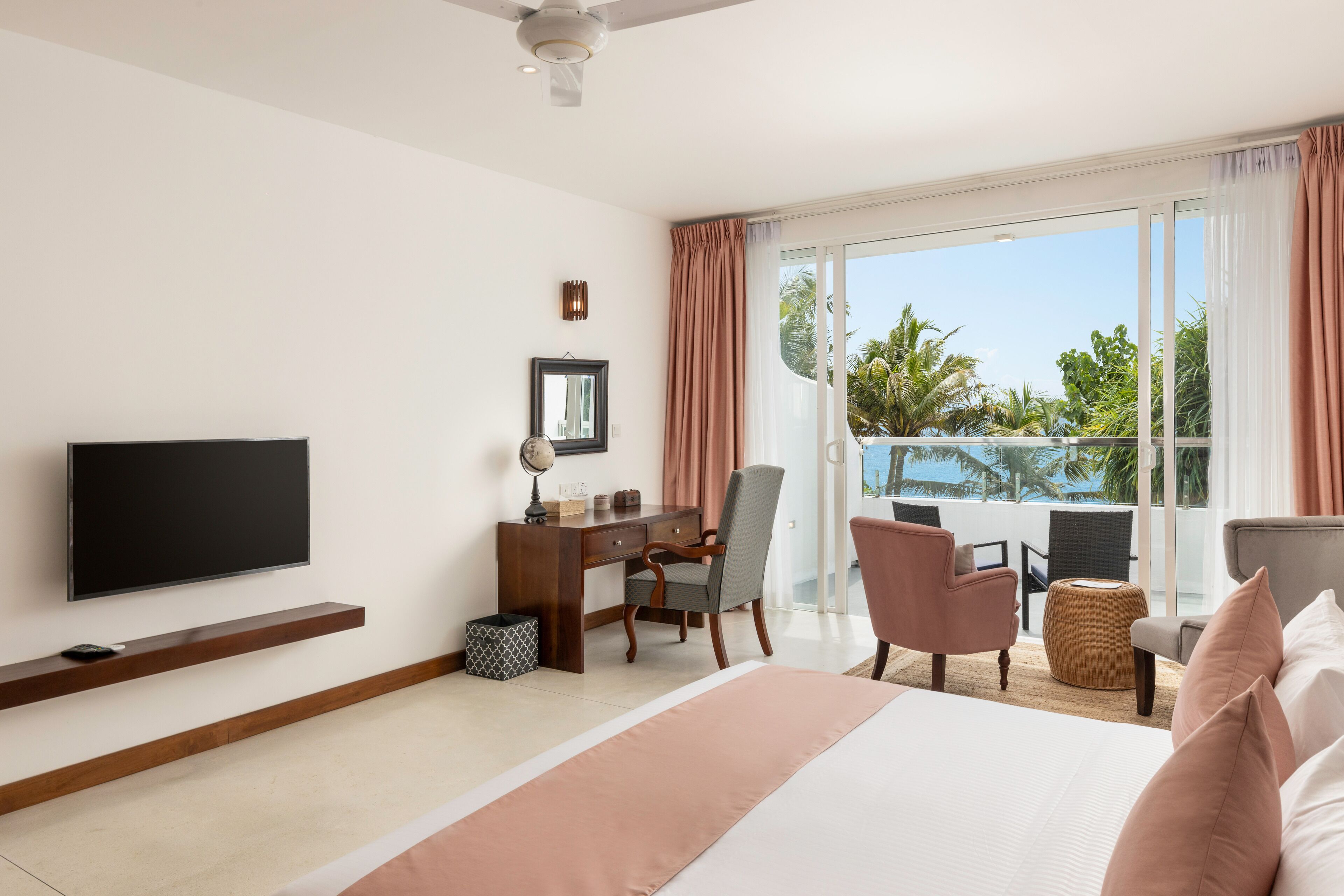 A hotel room with a bed, a desk, a chair, a television, and a view of the outdoors.