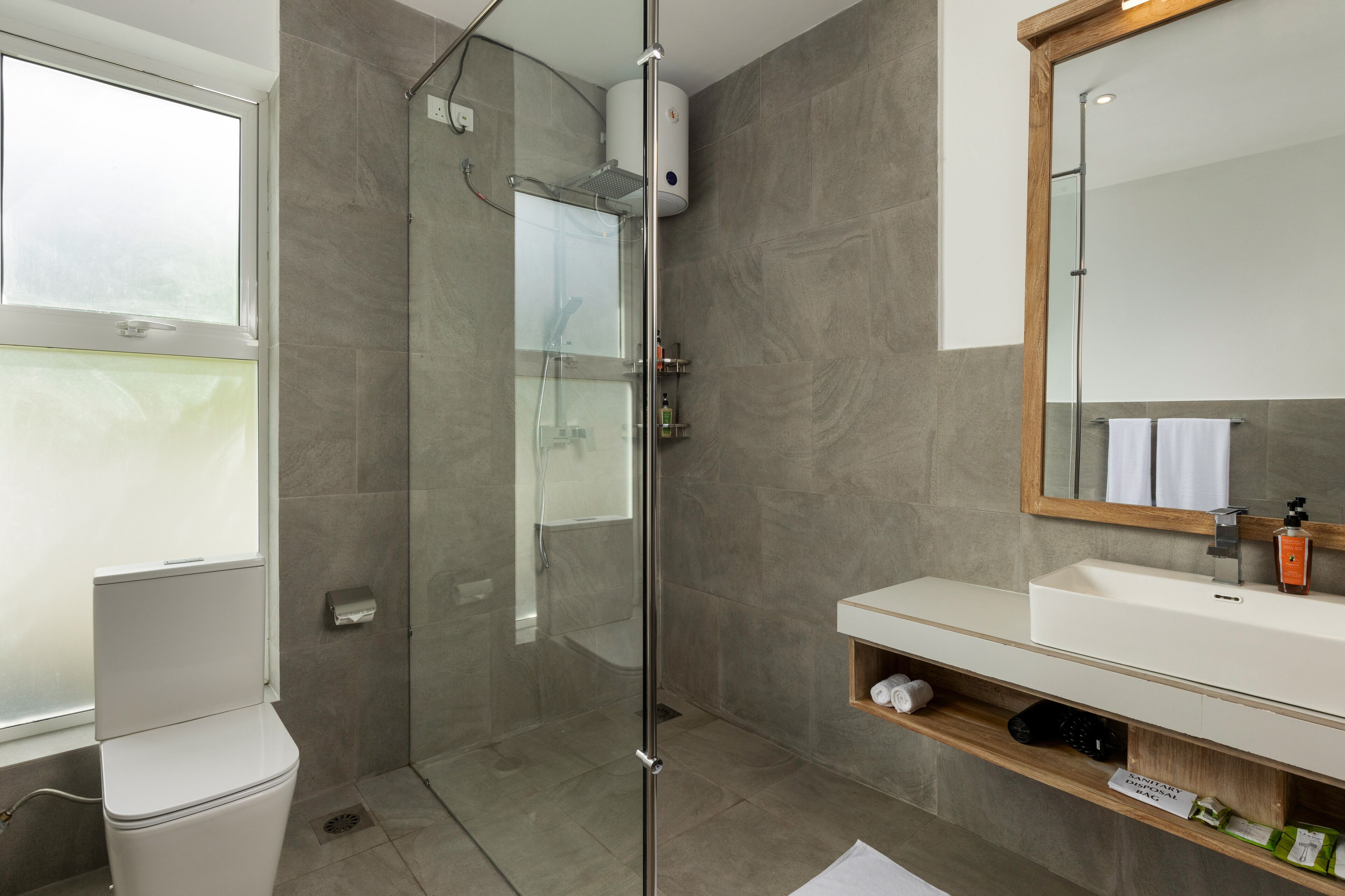 A modern bathroom with a glass-enclosed shower, a white sink, and a mirror above it.