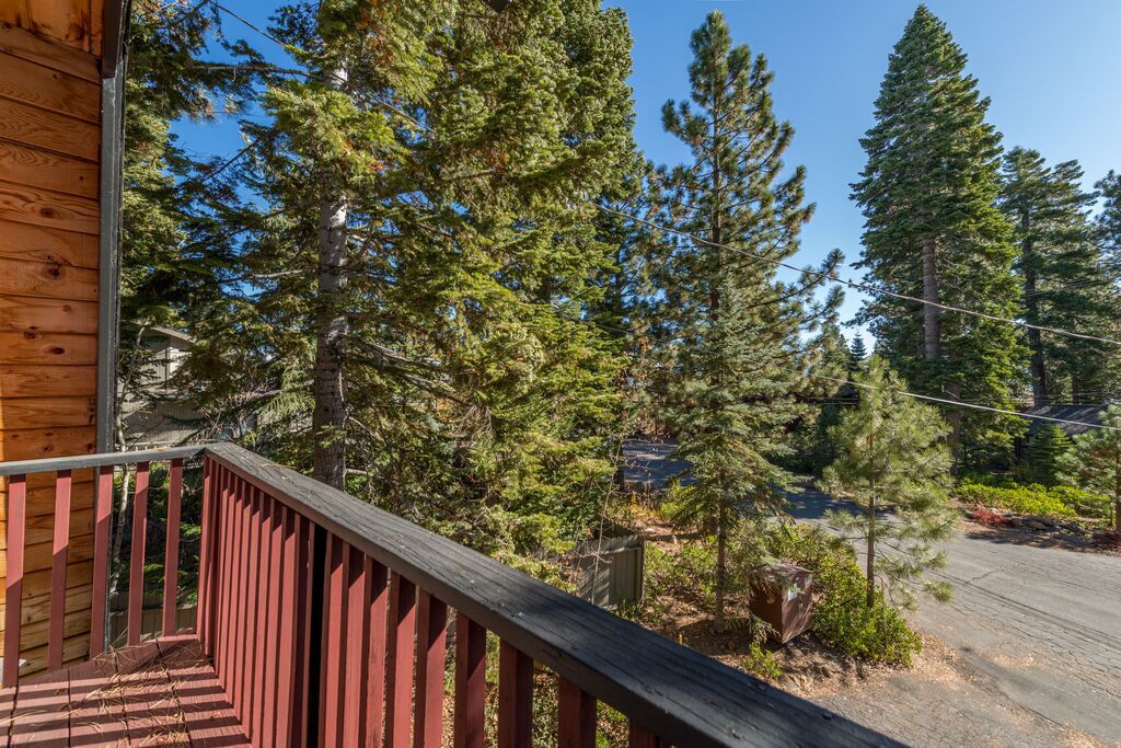 Une cabane en bois avec une balustrade rouge, entourée de grands arbres à feuilles persistantes.