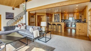 A spacious living area with a sofa, coffee table, and a staircase leading to an upper level. - Modern, Hot Tub, Lake View, Short Drive to Beach, Restaurants, and Shops- Flying Flamingo (Kings Beach)