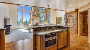 A spacious kitchen with a stone fireplace, large windows, and a wooden island with a built-in oven. - Modern, Hot Tub, Lake View, Short Drive to Beach, Restaurants, and Shops- Flying Flamingo (Kings Beach)