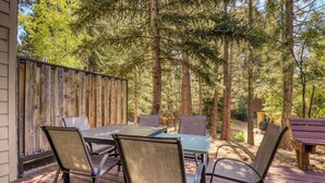 Une terrasse extérieure avec une plateforme en bois, une table et des chaises, et une clôture en bois.