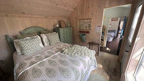 A wooden-paneled bedroom with a bed, dresser, and a mirror.