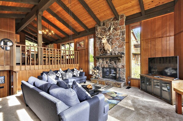 A cozy living room with a stone fireplace, a large sofa, and a television.