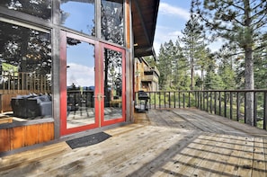 A wooden deck with glass doors leading to an outdoor seating area.